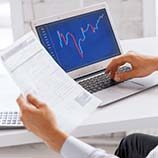 Person using laptop and holding paperwork
